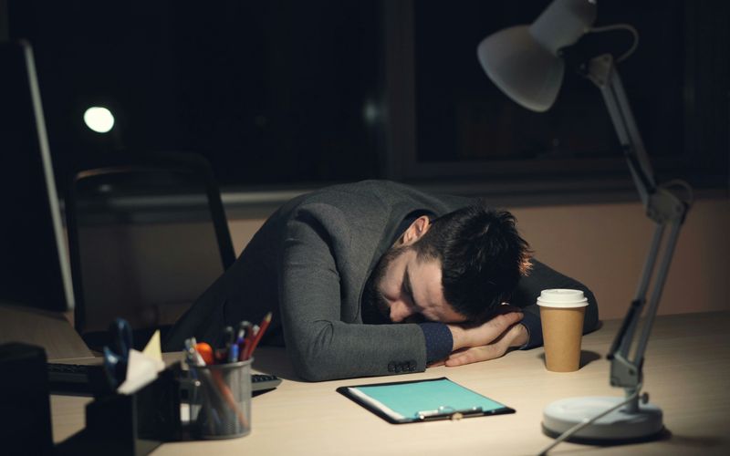 A man sleeping at the computer.